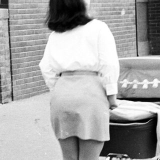 Woman walks away, pushing a vintage baby carriage.