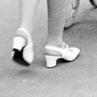 Woman walks away, pushing a vintage baby carriage.