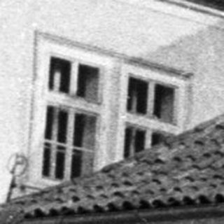 Black and white photo shows a building with a balcony.