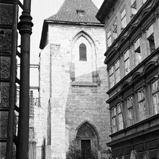 Stone tower with arched gateway, surrounded by buildings.