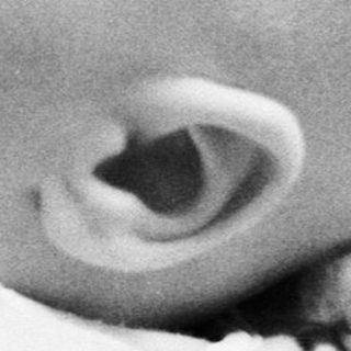 Baby lying on a textured blanket, looking upward.