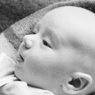 Baby lying on a textured blanket, looking upward.