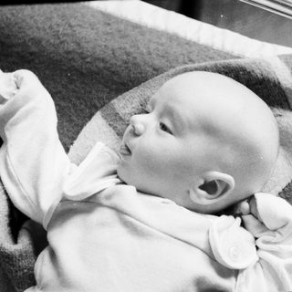 Baby lying on a textured blanket, looking upward.