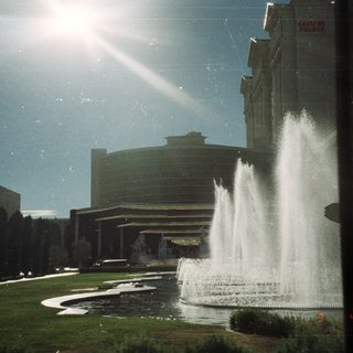 Fountain and Caesars Palace hotel visible under a bright sky.