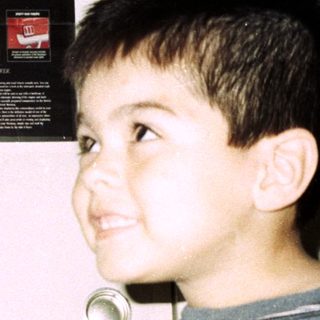 Boy points at "First Mustang" poster on a door.