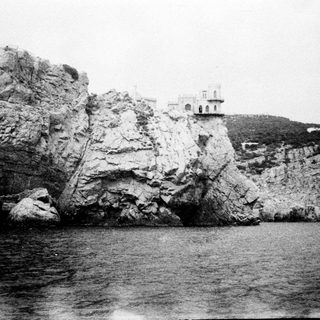 Rocky coastline with a building perched on a promontory.