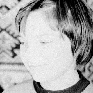 Woman holding baby, child standing nearby in a room.