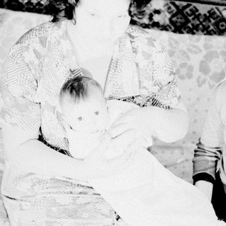 Woman holding a baby, with a child nearby.