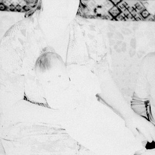 Black and white photo of a baby lying in a bed.