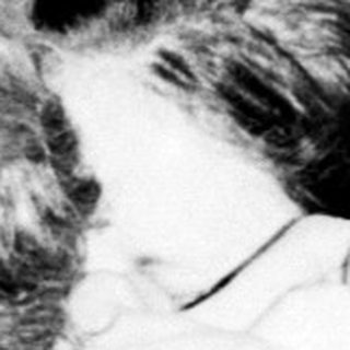 Here's a brief summary of the image: Man comforting a woman, seated on a sofa.