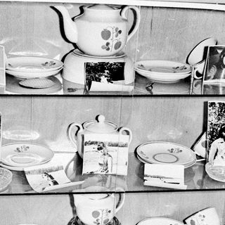 Vintage china displayed on shelves in a cabinet.