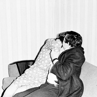 Here's a brief summary of the image: Couple embraces and kisses on a sofa.