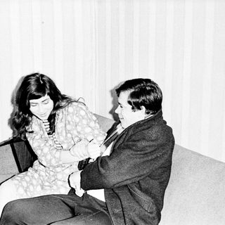 Couple seated on a couch, appearing to converse.