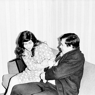 Couple seated on a couch, appearing to converse.
