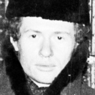 Man in coat stands near a complex electrical panel.