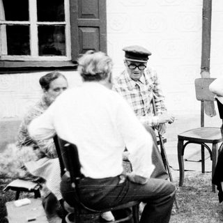 Group of people seated outdoors in a vintage setting.