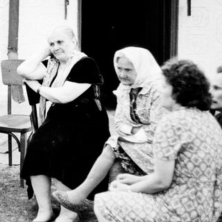 Group of people seated outdoors in a vintage setting.
