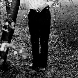 Man stands near a blossoming tree in a garden.