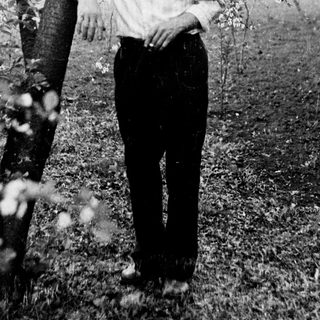 Man stands near a tree in a garden setting.
