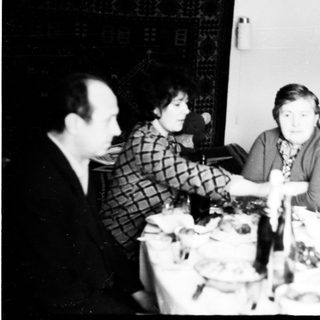 Here's a brief summary of the image: Family gathered around a table, seemingly having a meal.
