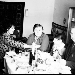 Here's a brief summary of the image: Family gathered around a table, seemingly having a meal.
