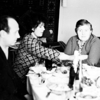 Here's a brief summary of the image: Family gathered around a table, seemingly having a meal.