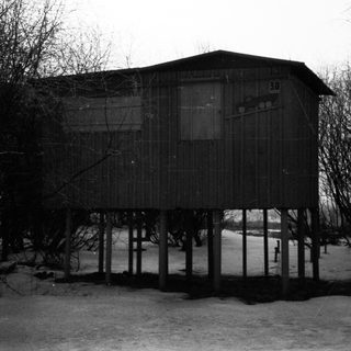 Elevated wooden structure stands in a snowy, wooded area.