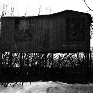 Elevated, weathered structure stands amidst sparse winter vegetation.
