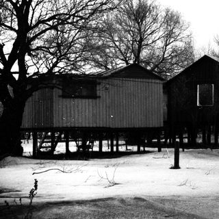 Elevated, weathered buildings stand in a snowy landscape.
