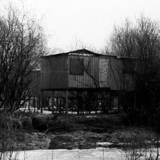 Elevated house surrounded by trees and icy water.