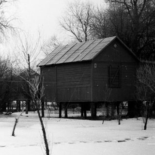 Elevated houses stand in a snowy, wintry landscape.