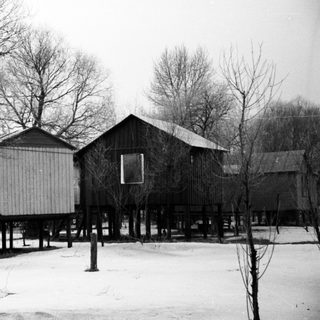 Elevated, weathered buildings stand in a snowy, barren landscape.