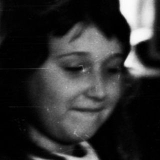 Young girl plays piano, seated in a vintage room.