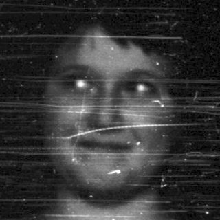 Here's a brief summary of the image: Faded black and white portrait of a person in a dress.