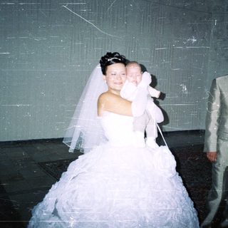 Bride and groom with baby in a wedding photo.