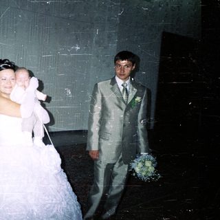 Bride and groom with baby in a wedding photo.