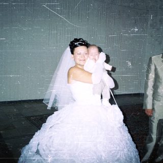 Bride and groom with baby in a wedding photo.