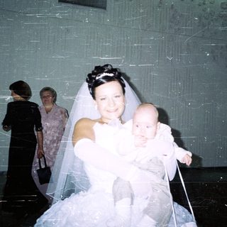 Bride holding baby, with guests in the background.