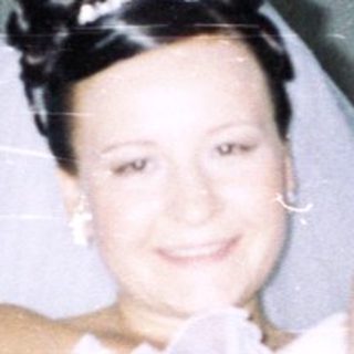 Bride holding baby, with guests in the background.