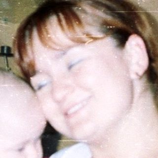 Woman holding a baby in a home setting.