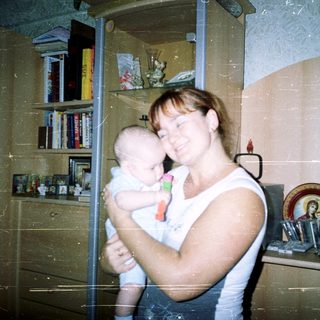 Woman holding a baby in a home setting.