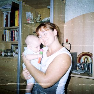 Woman holding a baby in a home setting.