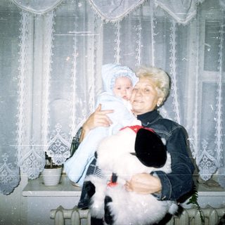 Woman holding a baby and a fluffy dog.