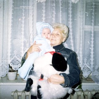 Woman holding a baby and a fluffy dog.