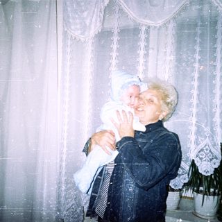 Woman holding a baby in front of a window.