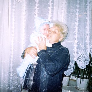 Woman holding a baby in front of a window.