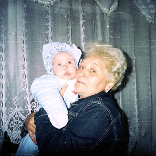 Woman holding a baby, smiling, in a home setting.