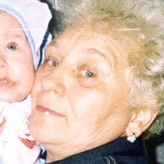 Woman holding a baby, smiling, in a home setting.
