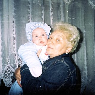 Woman holding a baby, smiling, in a home setting.