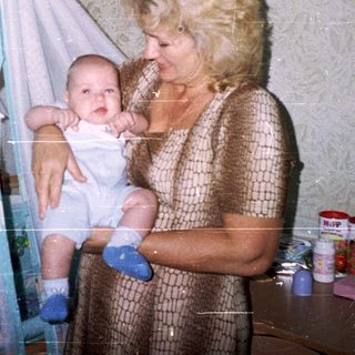 Woman holding a baby in a bedroom with a playpen.
